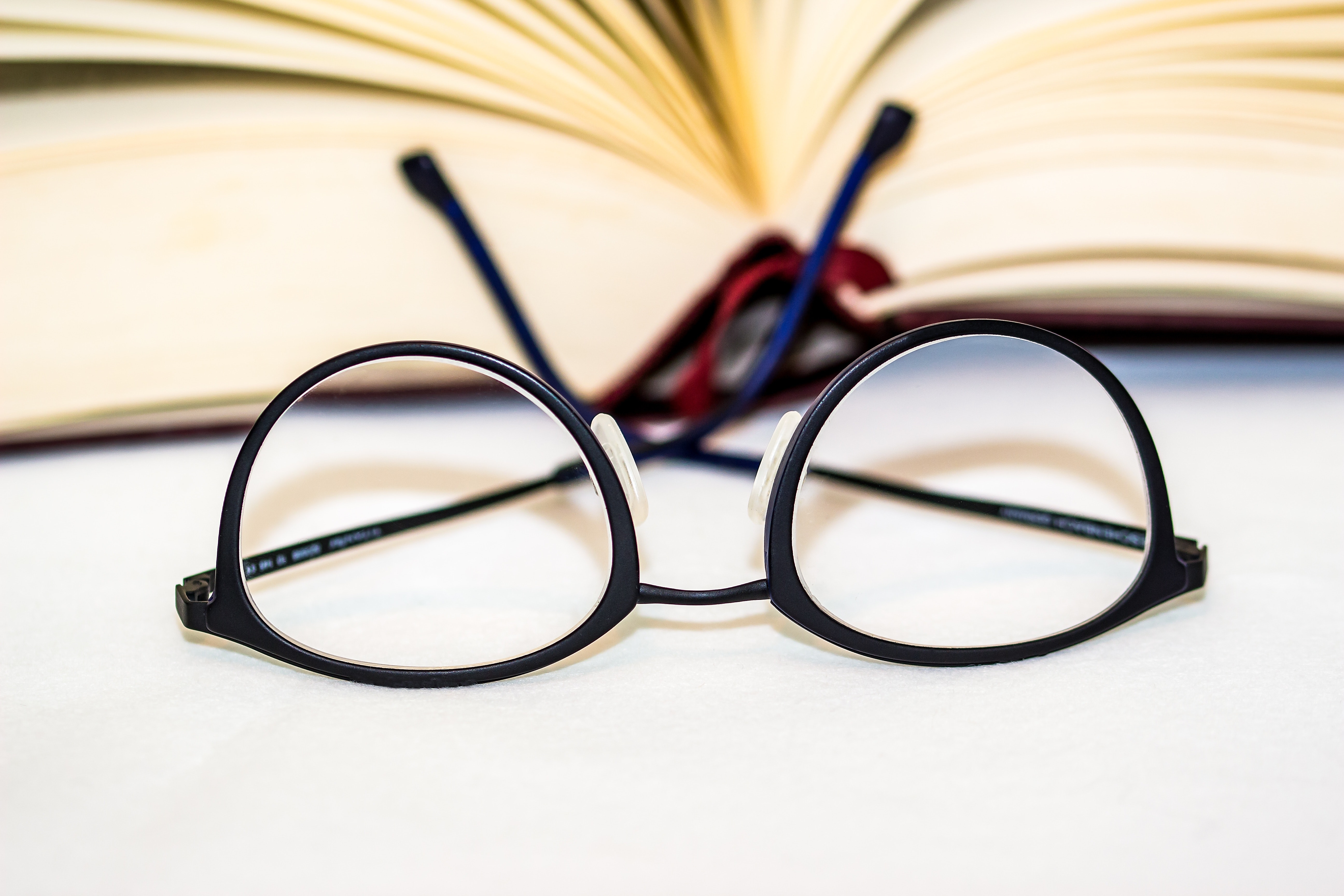 A pair of black glasses rests upside in front of a book