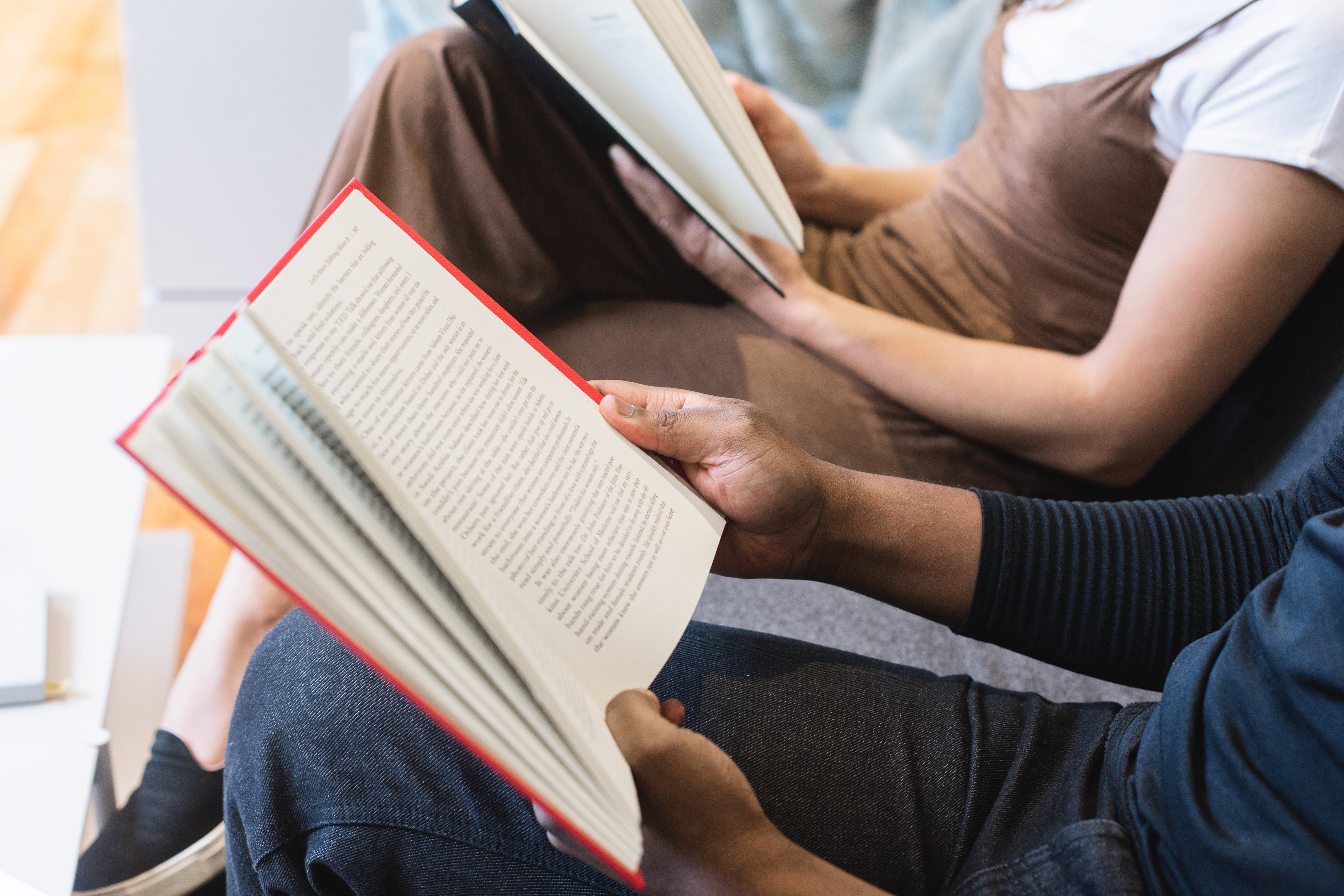 Two adults read books next to each other